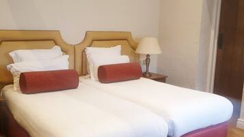A double bed with two red headboards, white bedding, and a bedside lamp.