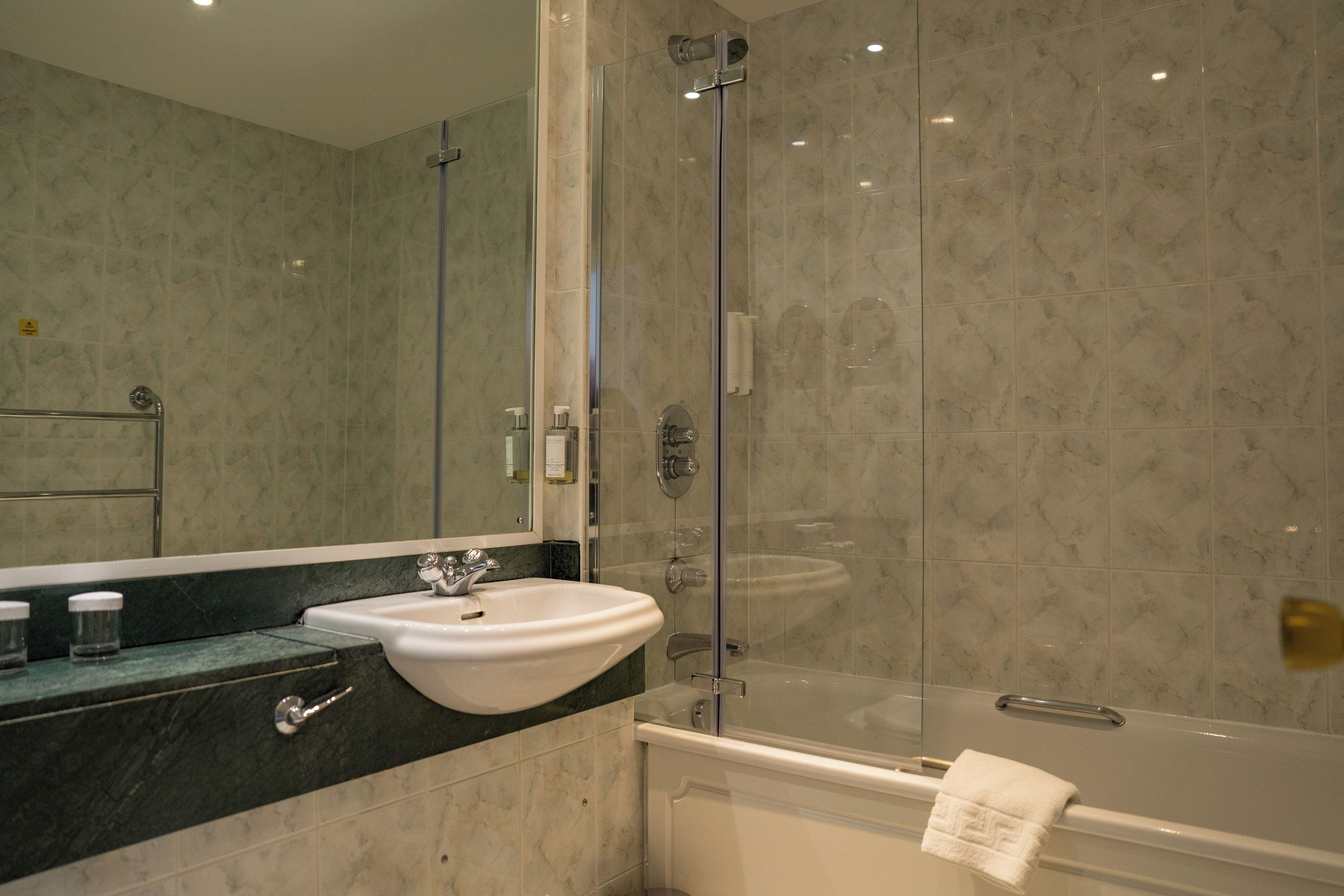 A modern bathroom with a glass-enclosed shower, a white sink, and a bathtub.