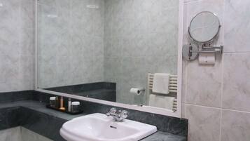 A bathroom with a white sink, a mirror, and a towel rack.