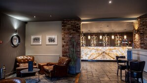 A lobby with leather sofas, a marble bar, and a stone floor. -  Windmill Village Hotel, Golf Club & Spa, BW Signature Collection (Coventry)