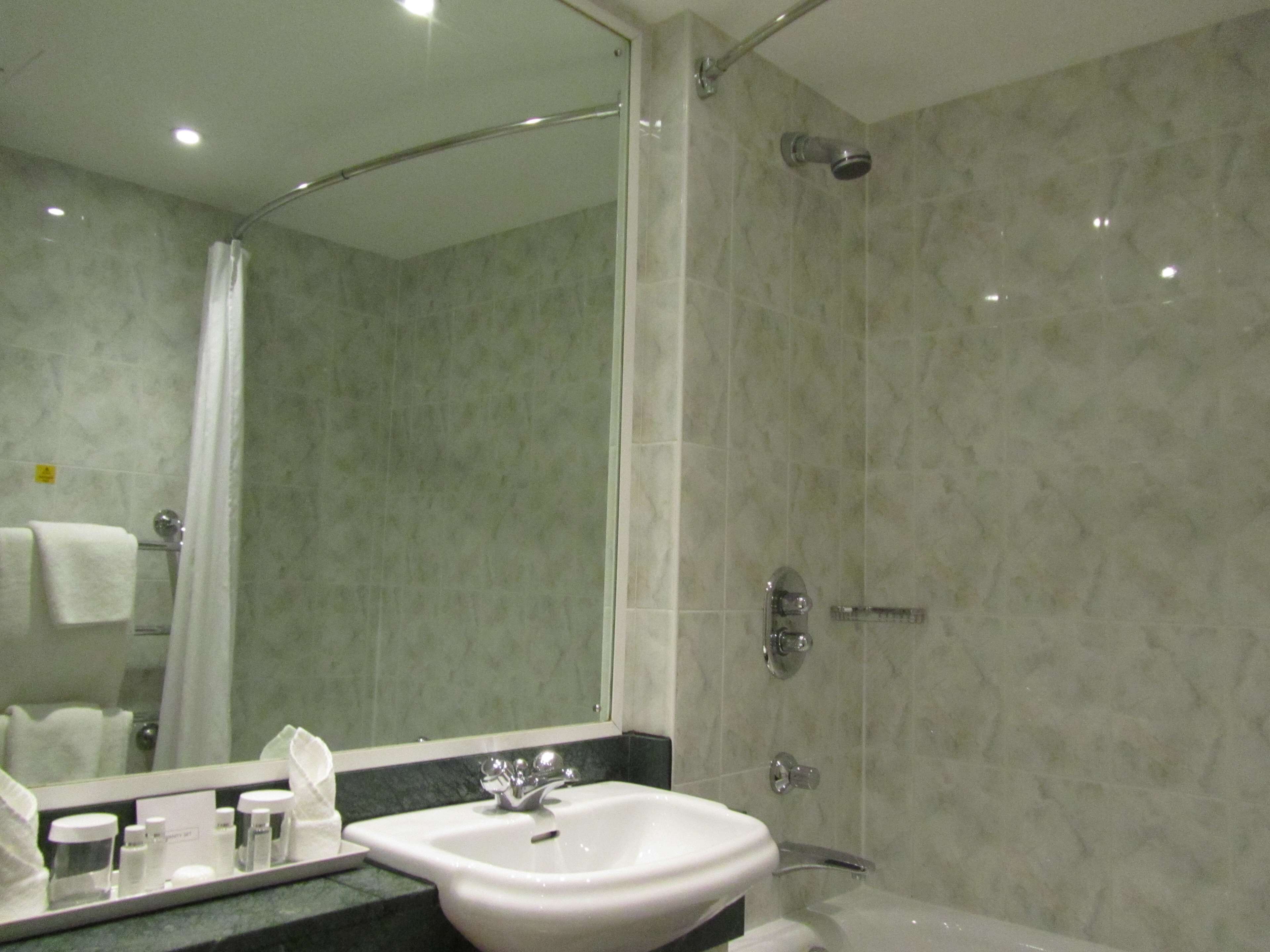 A modern bathroom with a glass shower enclosure, a sink with a mirror, and a towel rack.