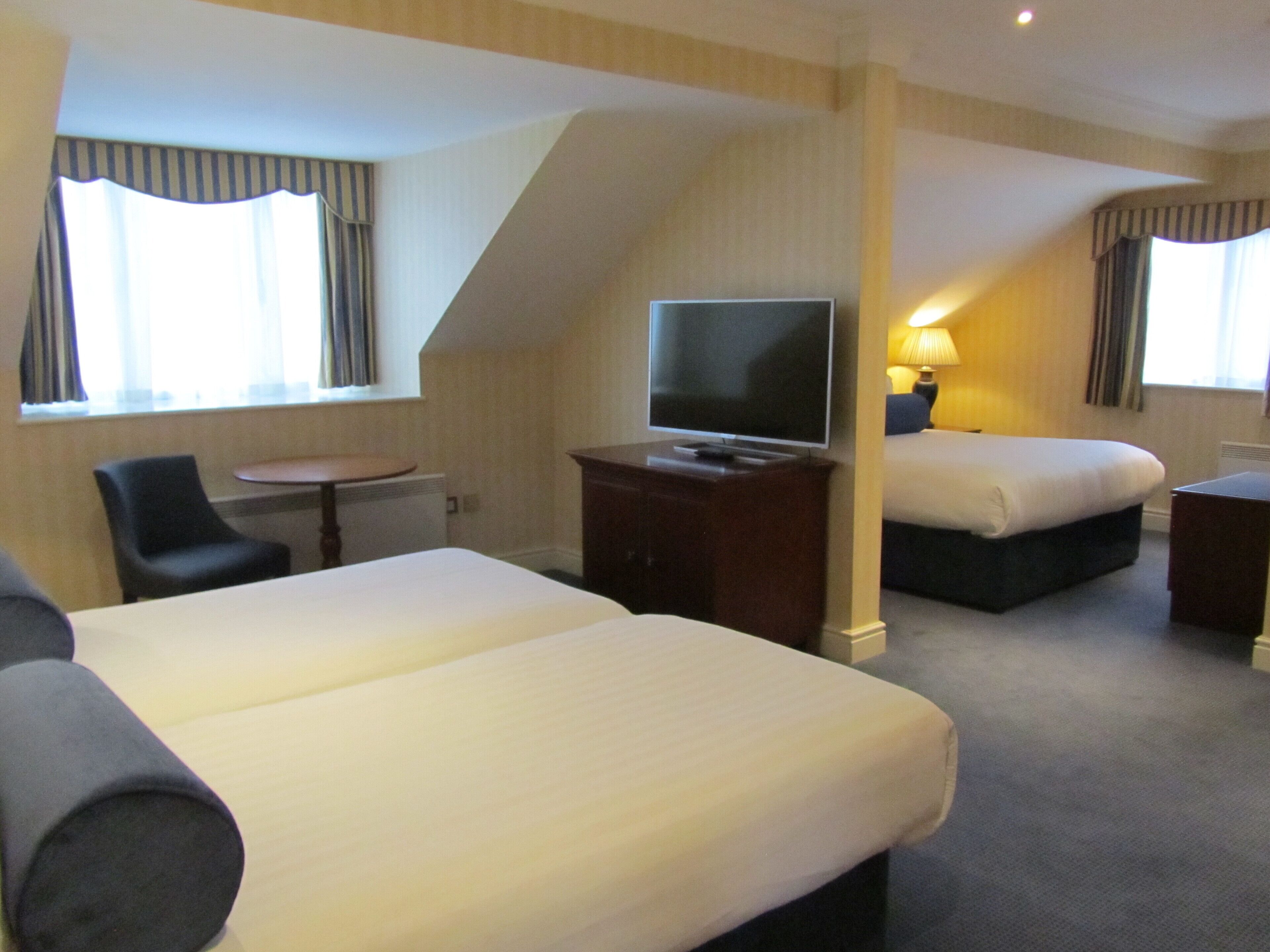 A hotel room with two beds, a TV, a desk, and a chair.