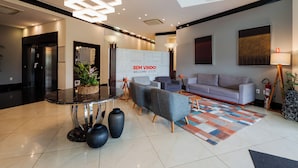 A modern lobby with a reception desk, sofas, a patterned rug, and a 'WELCOME' sign. - Intercity Vinhedo (Vinhedo)