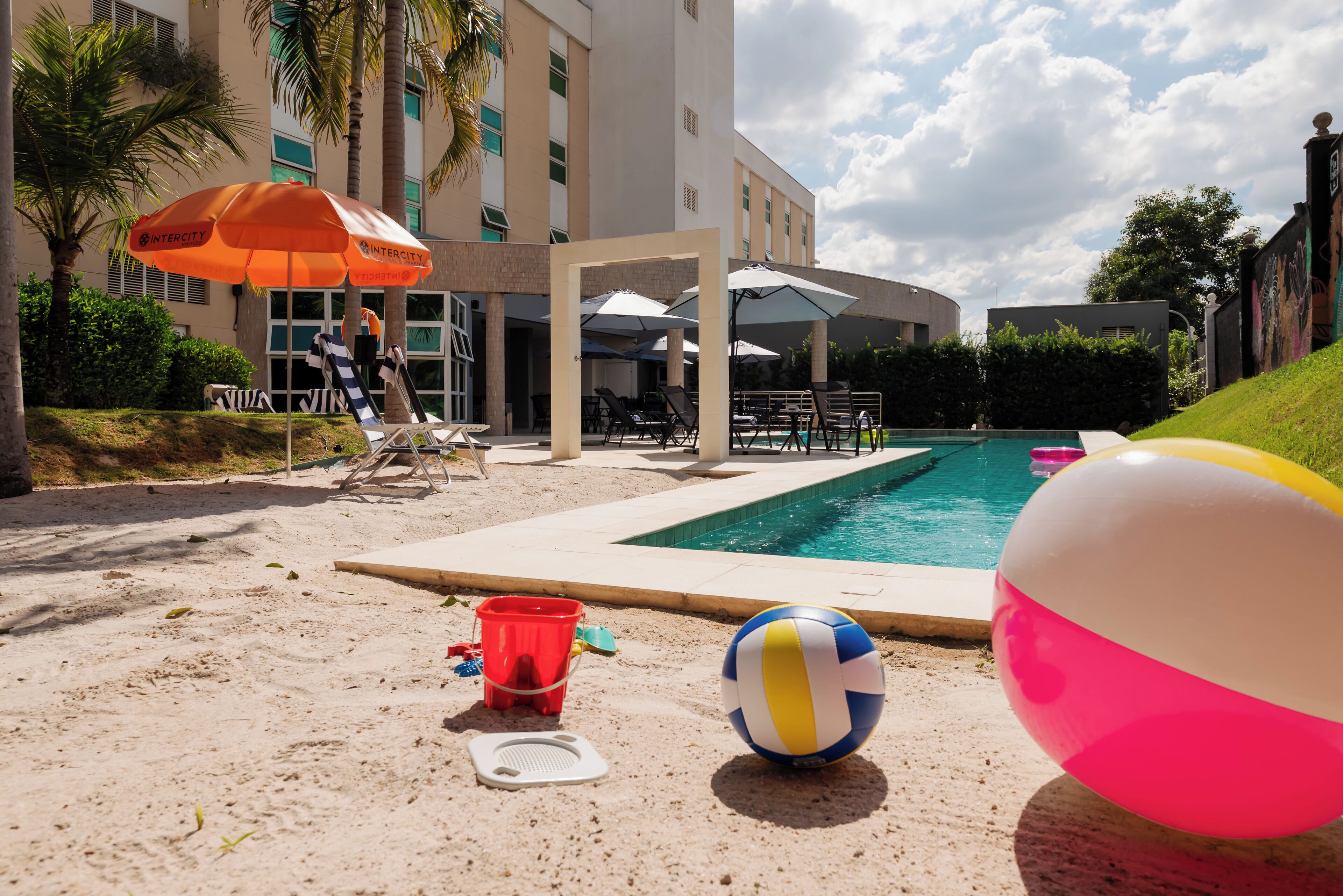 A poolside area with umbrellas, lounge chairs, and a volleyball.