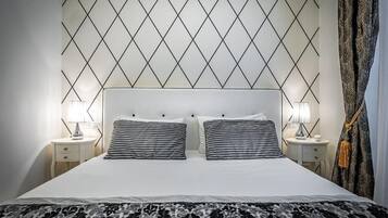 Een hotelkamer met een bed, twee nachtkastjes en een gestreept hoofdeinde.
