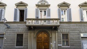 Un bâtiment doté d’une grande porte en bois, d’un balcon orné de balustrades et d’une façade en pierre.