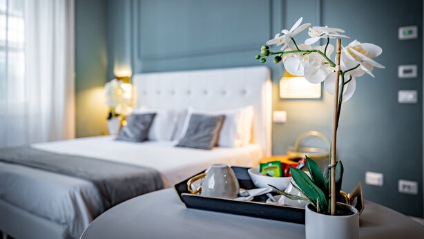 Une chambre d’hôtel avec un lit, une table de chevet et une orchidée en pot.
