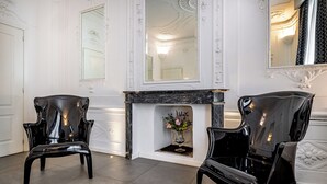 Une pièce avec deux chaises noires, une cheminée et un miroir au mur.