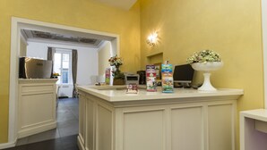 Une cuisine dotée d’un îlot central, d’un réfrigérateur et d’un four à micro-ondes. L’îlot est agrémenté de compositions florales, et un piédestal blanc surmonté de fleurs y est également placé.
