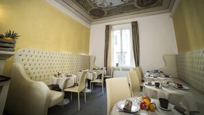 Un espace repas doté d’un plafond haut, d’un décor orné et offrant une vue sur l’extérieur grâce à une fenêtre.