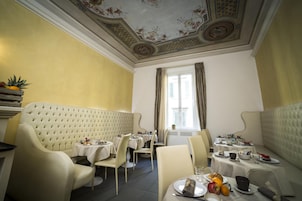A dining area with a high ceiling, ornate ceiling design, and a view of the outdoors through a window.