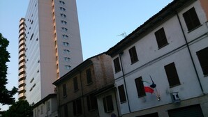Un grand immeuble moderne, doté de nombreuses fenêtres, et un bâtiment plus ancien, orné d’un drapeau et d’une enseigne.