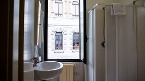 Une salle de bain avec une grande fenêtre, un lavabo et une douche.