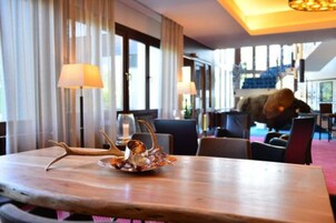 Un coin repas avec une table en bois, deux lampes et un centre de table décoratif en forme de bois de cerf.