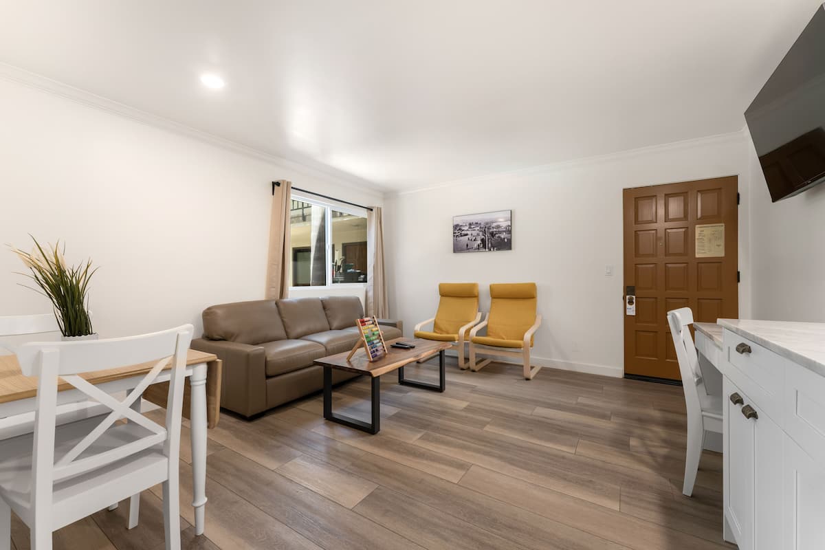 A modern living room with a sofa, two armchairs, a coffee table, and a dining table.