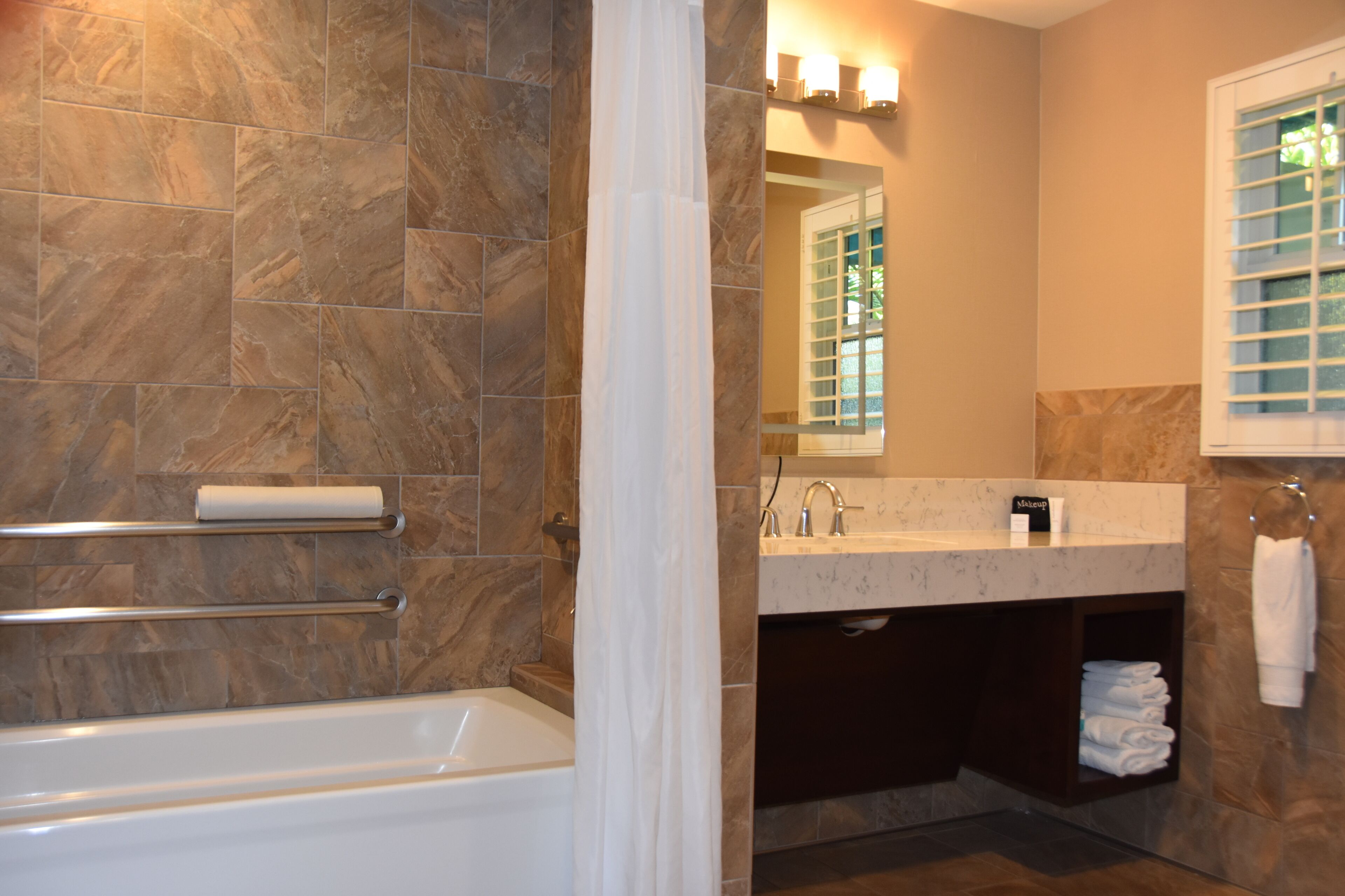 A bathroom with a bathtub, a vanity with a mirror, and a towel rack.