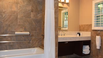 A bathroom with a bathtub, a vanity with a mirror, and a towel rack.