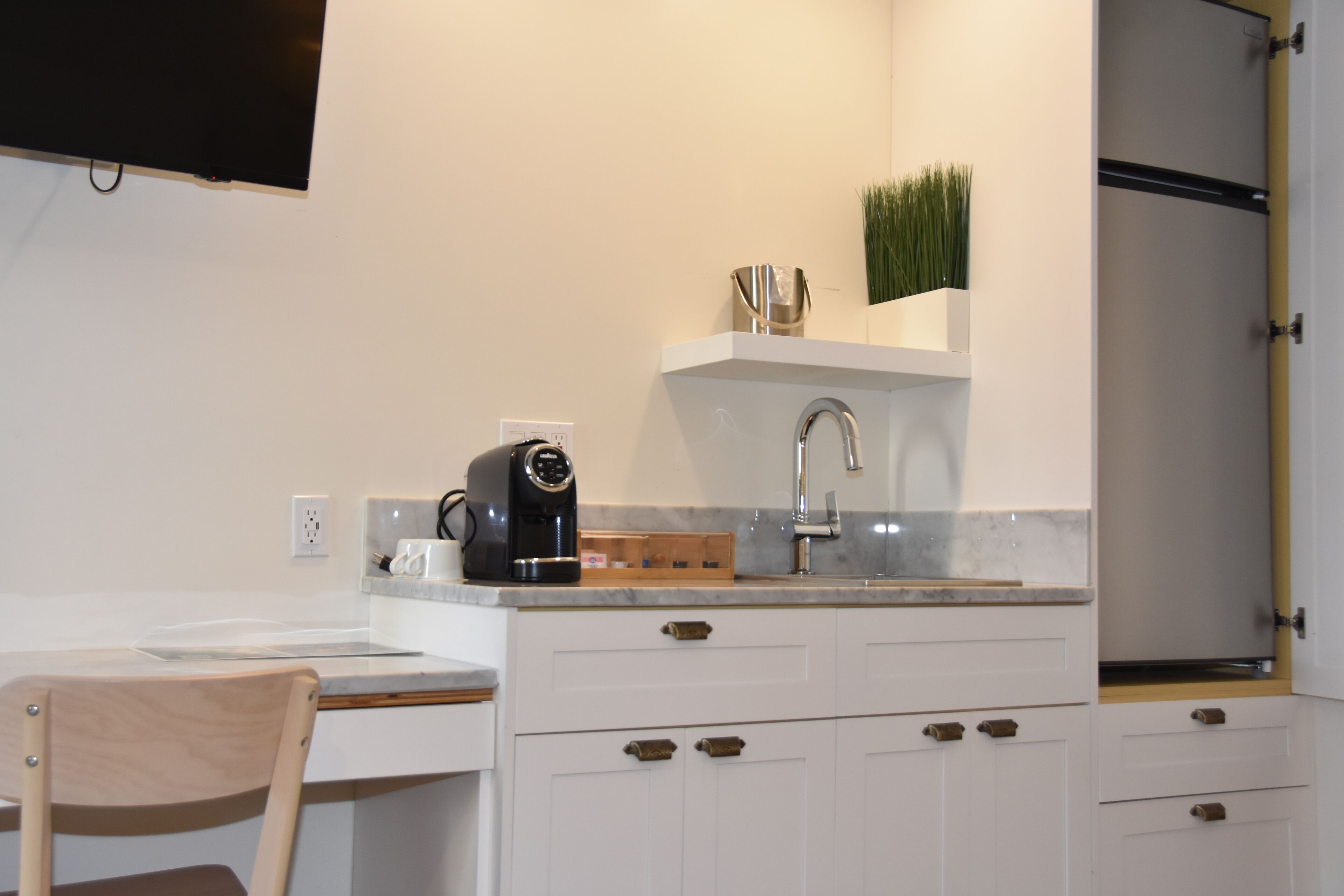A compact kitchen with a built-in coffee maker, a sink, and a small countertop.