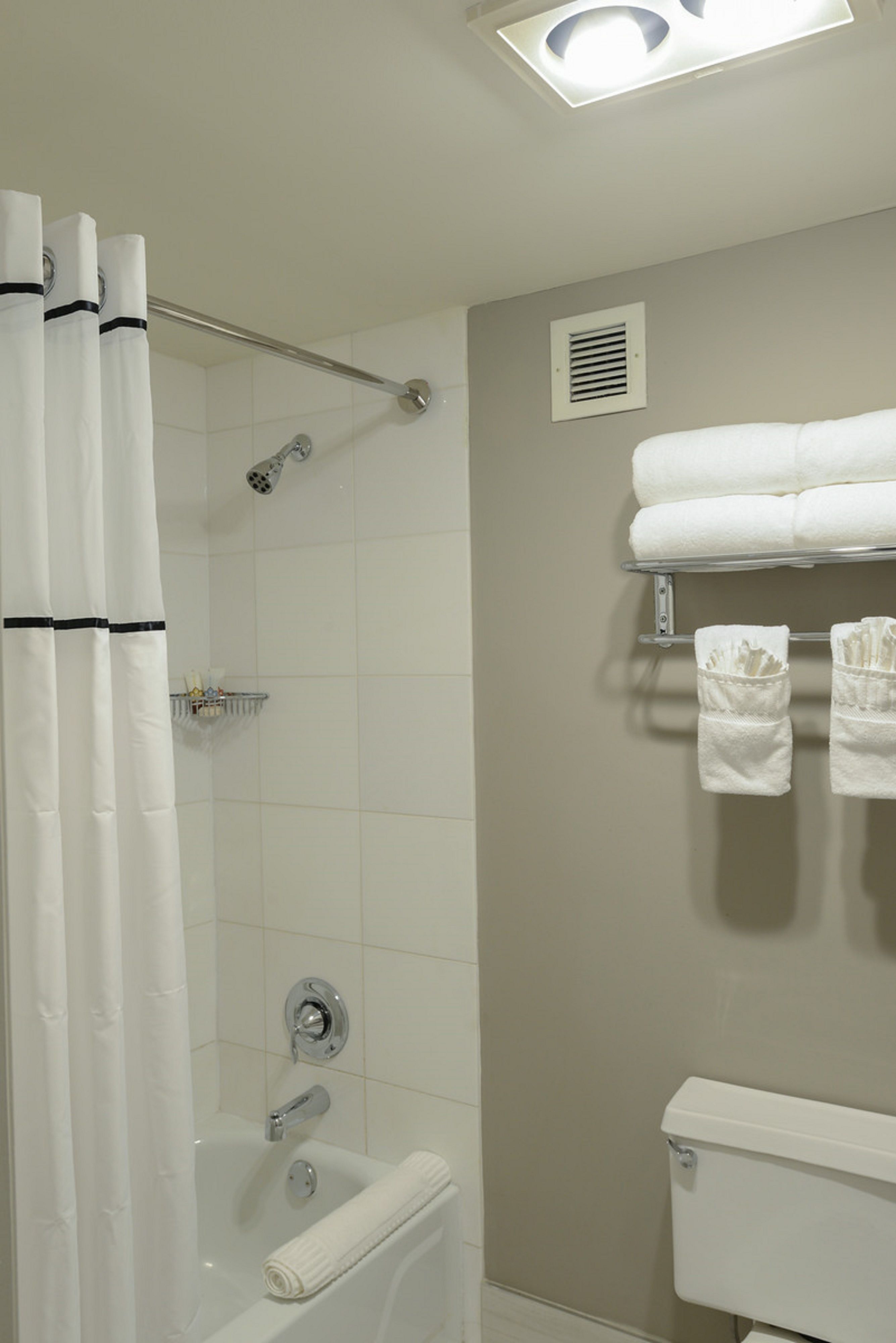 Un baño con ducha, inodoro y perchero para toallas.