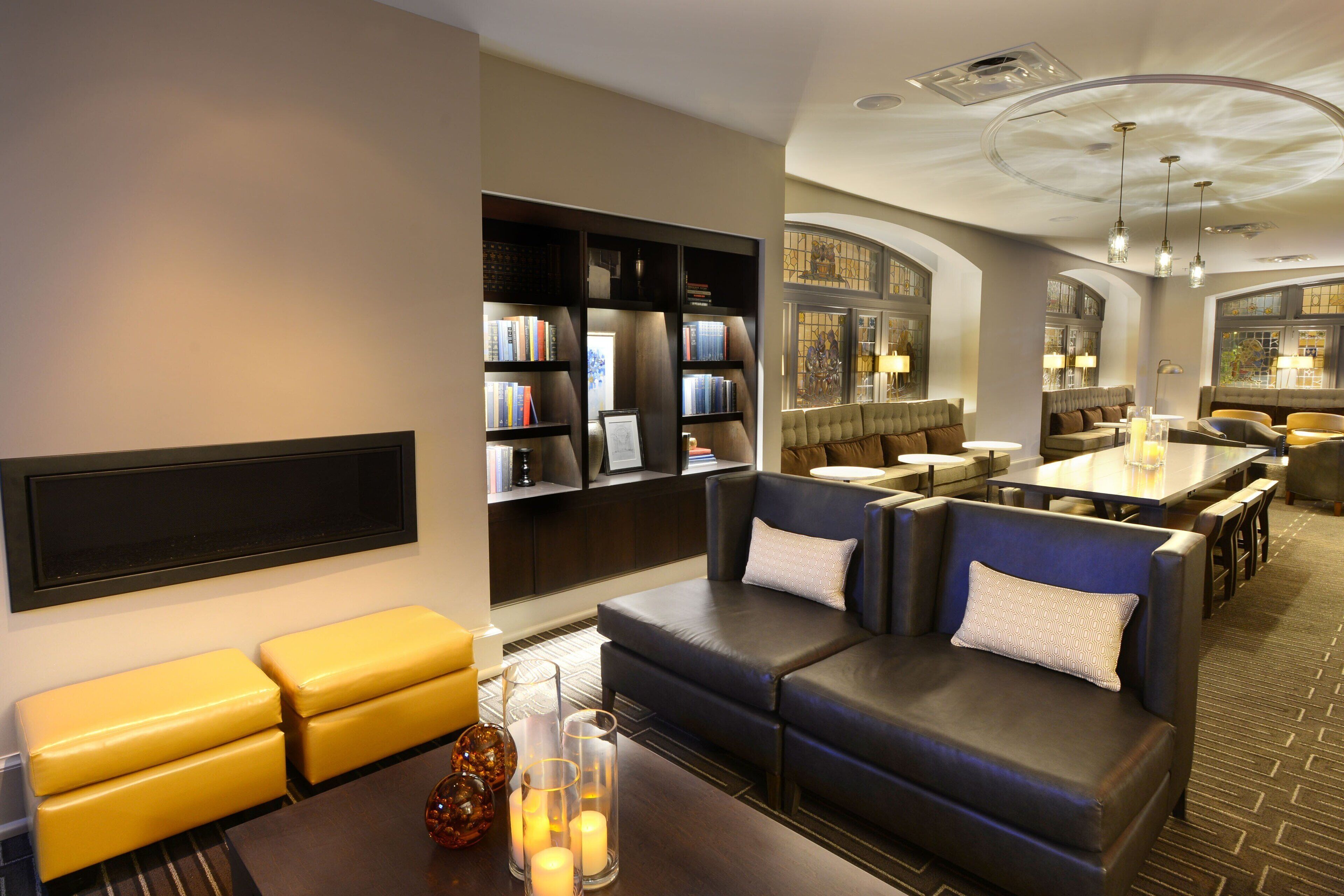 A modern lounge area with leather sofas, a bookshelf, and a dining area.