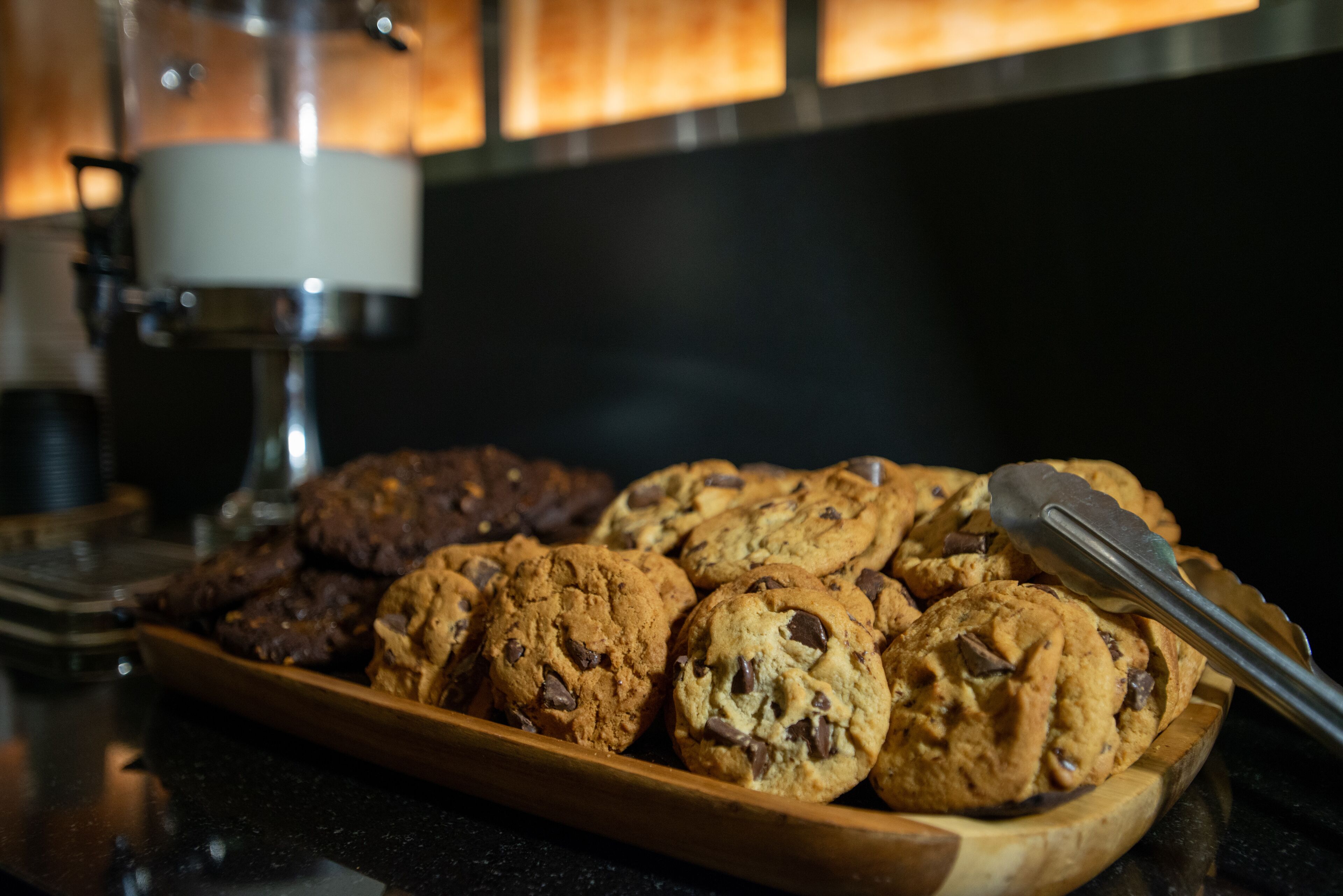 A wooden tray filled with chocolate chip cookies on a kitchen counter.