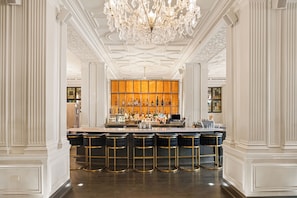 A bar area with a bar counter, stools, and a chandelier. - Magnolia Hotel St. Louis, a Tribute Portfolio Hotel (St. Louis)