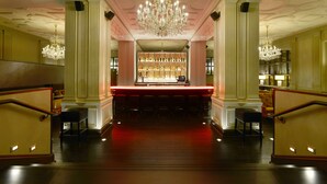 A grand lobby with a bar area, ornate chandeliers, and a staircase. - Magnolia Hotel St. Louis, a Tribute Portfolio Hotel (St. Louis)