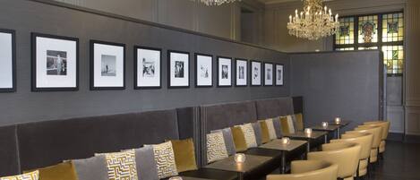 A row of seating with a row of framed photographs on the wall behind.