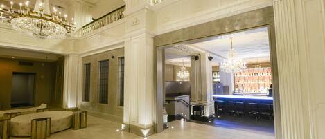 A grand lobby with a bar area, chandeliers, and seating.