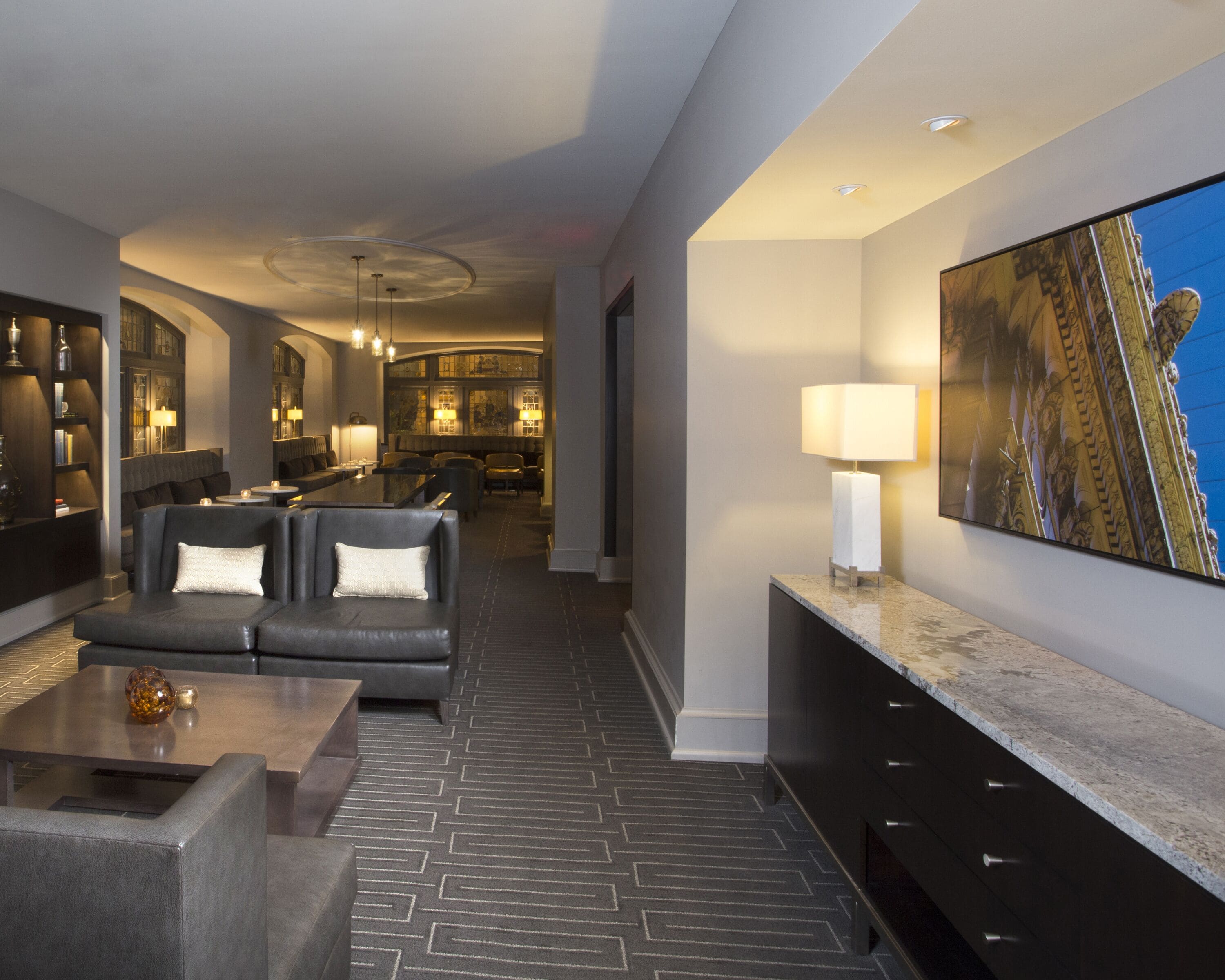 A modern hotel lobby with a dark leather sofa, a marble reception desk, and a large abstract painting on the wall.
