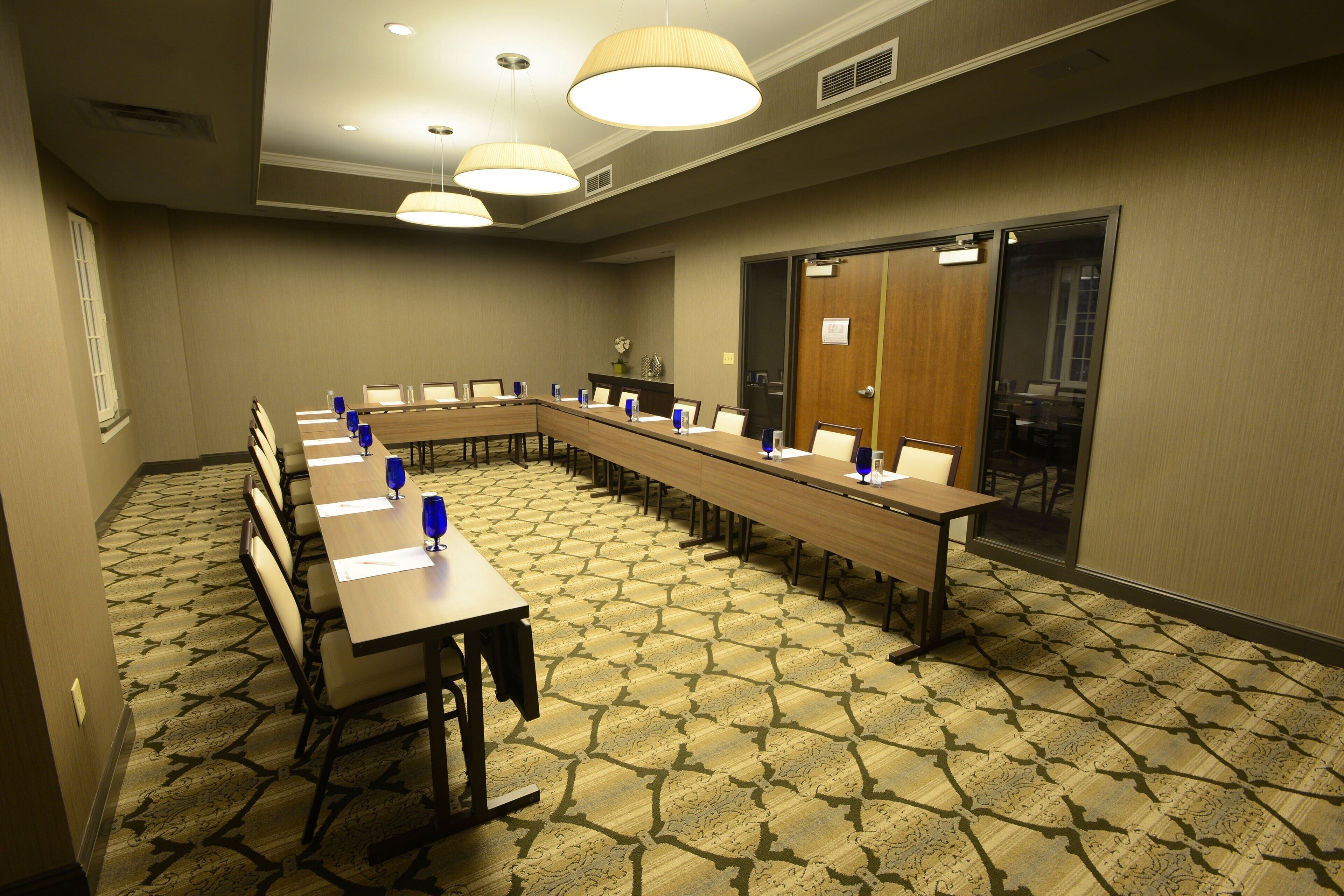 A conference room with a long table, chairs, and blue water glasses.