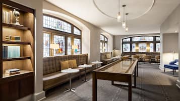 A spacious lounge area with a billiards table, comfortable seating, and a large window with stained glass.