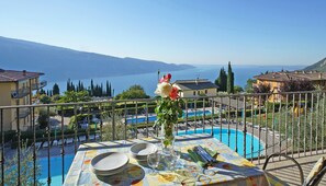 A terrace with a dining table set for four, overlooking a swimming pool and a mountainous landscape. - Residence Besàss (Tignale)