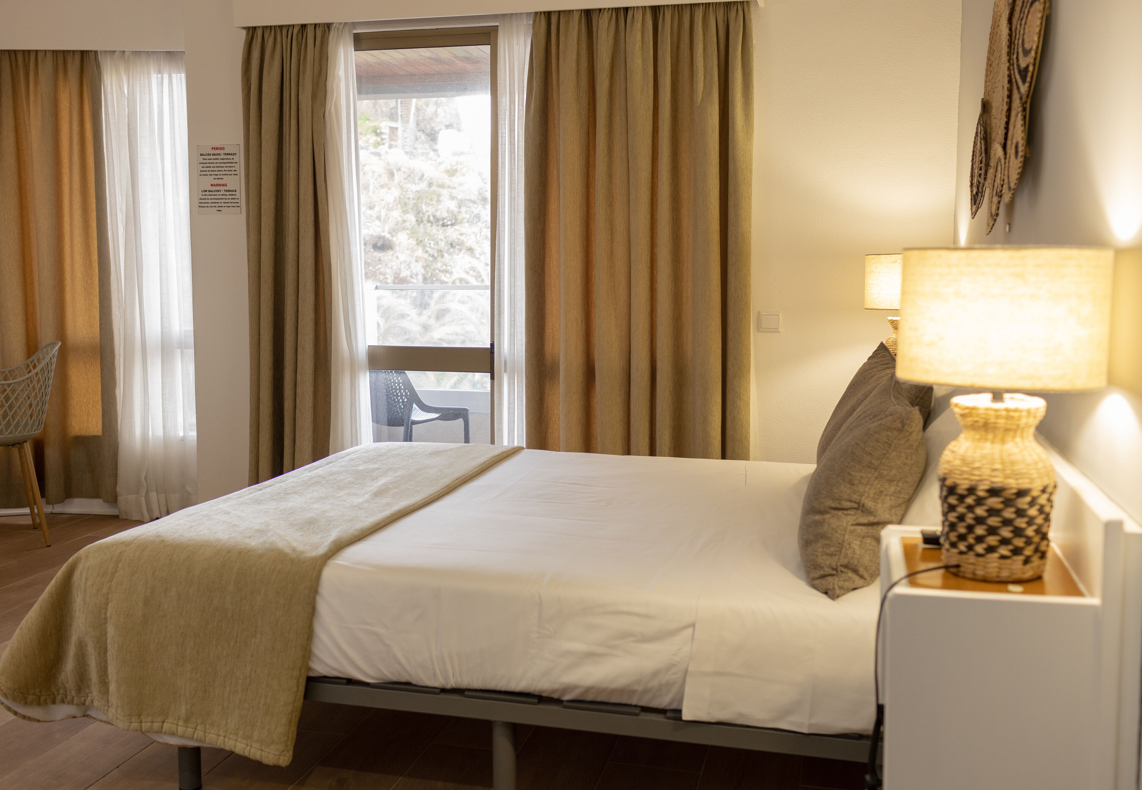 Una habitación de hotel con una cama, una silla, una lámpara y cortinas.