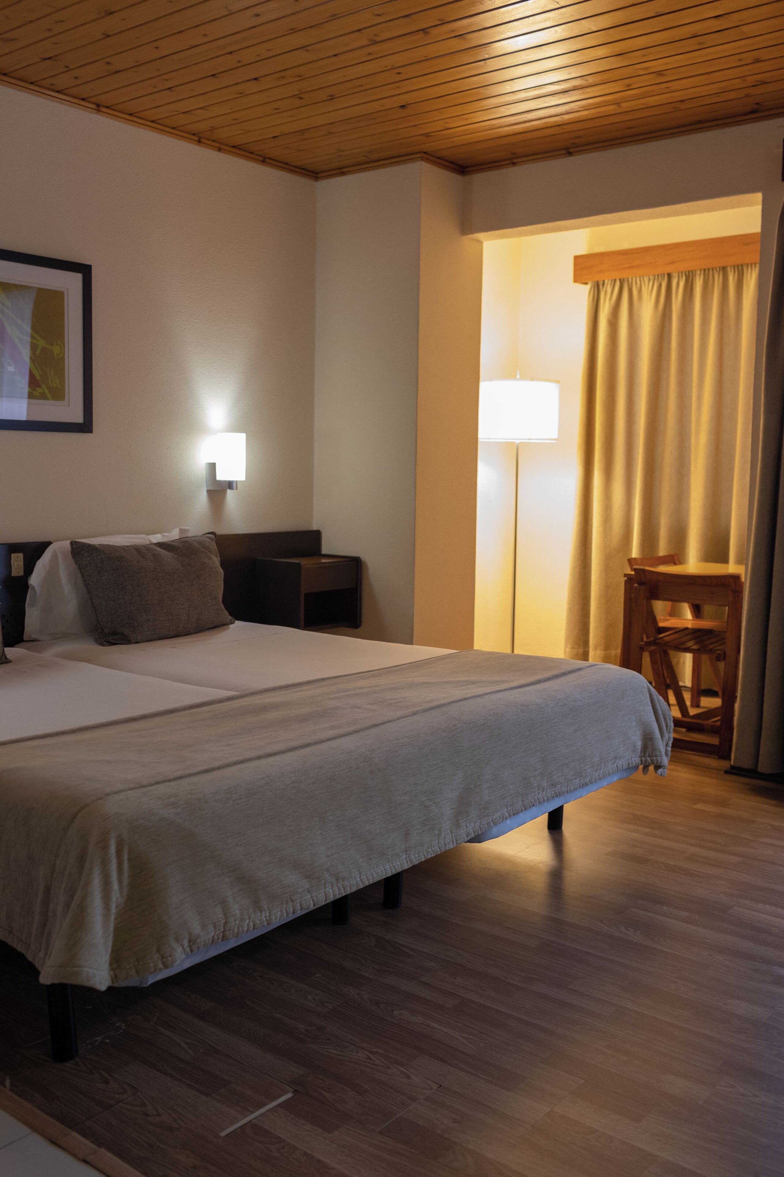 A hotel room with a large bed, a nightstand, a desk, and a chair.