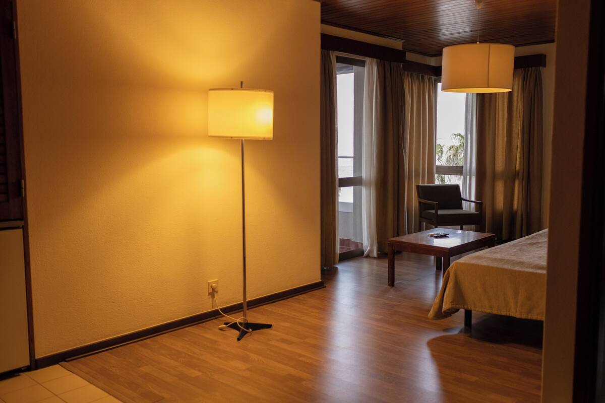 Ein Hotelzimmer mit Holzboden, einem Bett, einem Schreibtisch, einem Stuhl und einer Lampe.