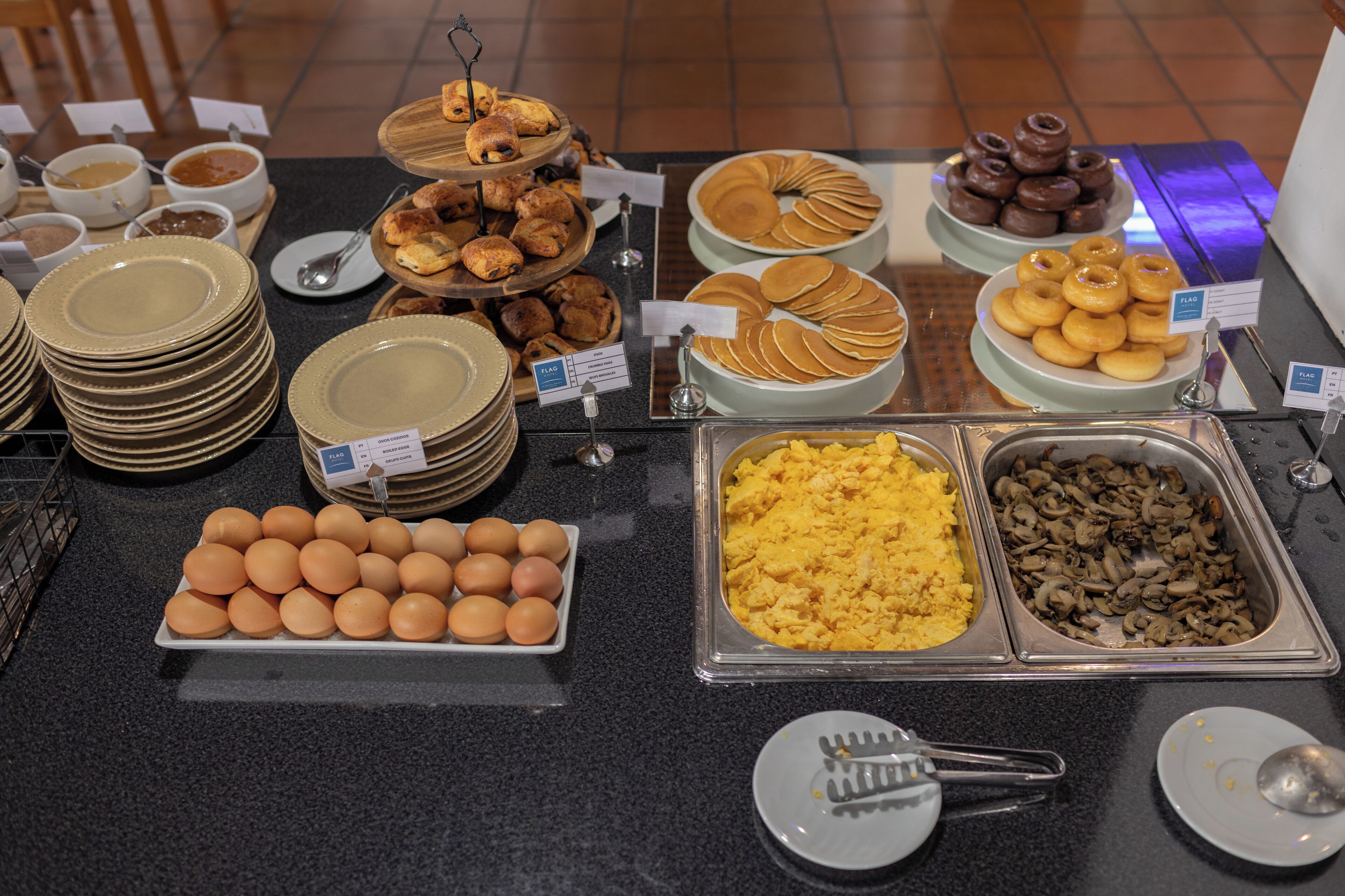 A buffet with various food items including eggs, pancakes, and muffins.