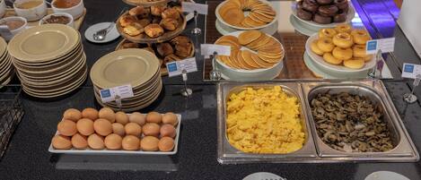 A buffet with various food items including eggs, pancakes, and muffins.