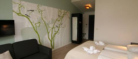 Une chambre d’hôtel moderne équipée d’un lit, d’un canapé et d’un téléviseur fixé au mur.
