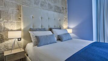 A neatly made bed with a tufted headboard, a bedside lamp, and a blue throw blanket.