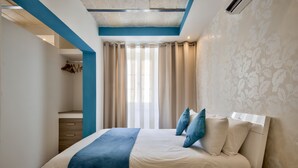 Un dormitorio con cama, mesita de noche, cómoda y ventana con cortinas.