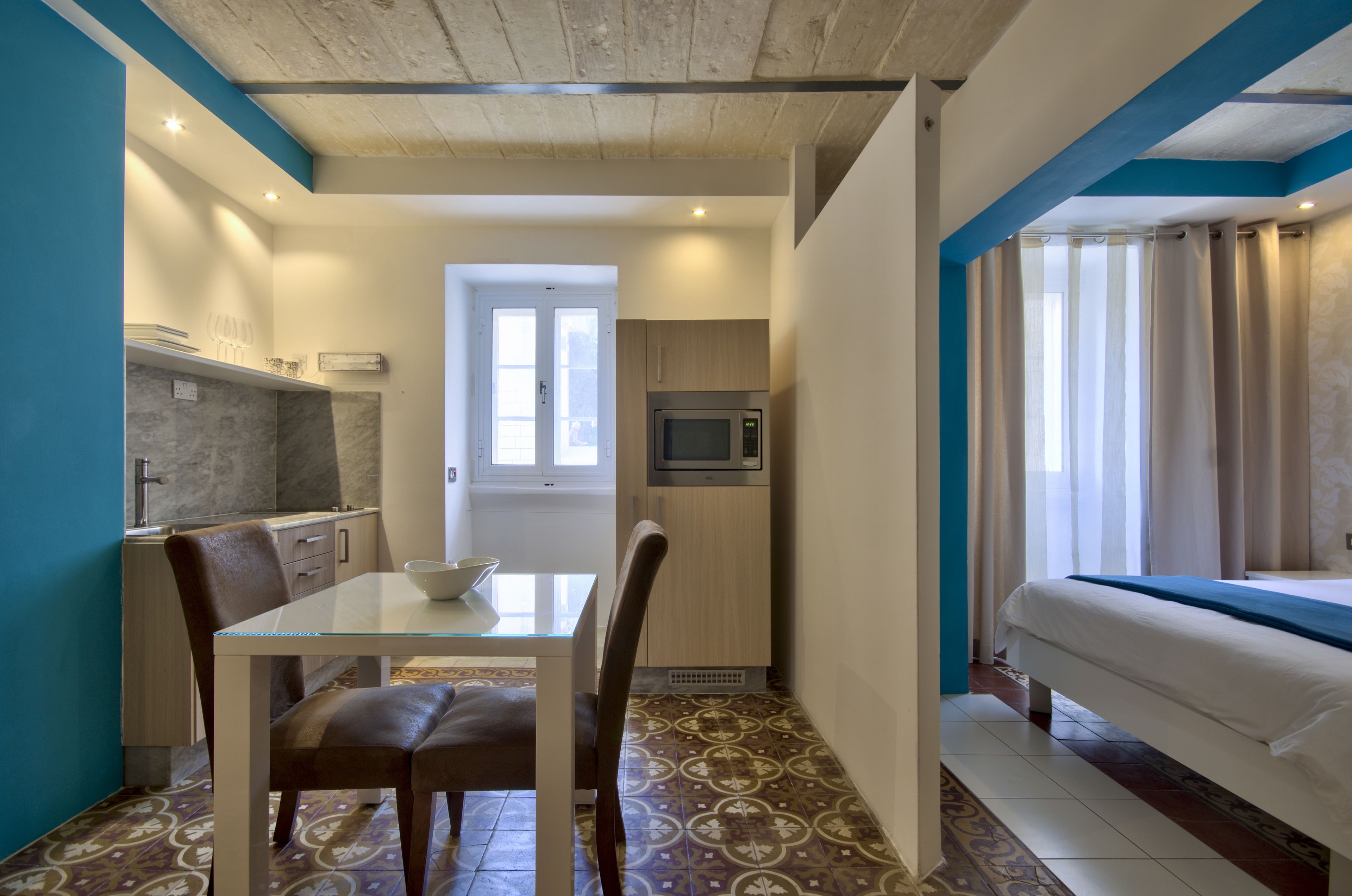 Una camera d'albergo compatta con angolo cottura, zona pranzo e un letto.
