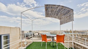 Una terraza en la azotea con mesa y sillas, una pérgola y vistas de la ciudad.