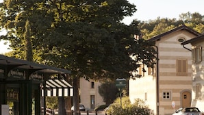 An outdoor café with tables and chairs, a green awning, and a building in the background. - Hotel Le Foresterie Dei Piaceri Campestri (Varese)