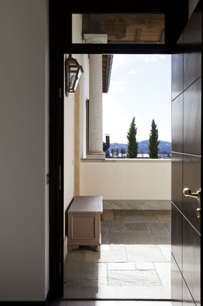 Ein Zimmer mit Blick auf Berge durch ein Fenster, eine kleine Bank und eine Tür, die nach draußen führt.