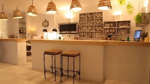 Zona de bar con dos taburetes, lámparas colgantes, un reloj y un monitor de computadora.