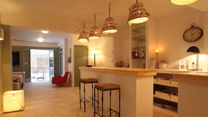 Una cocina moderna con una isla central, taburetes de bar, luces colgantes y un reloj en la pared.