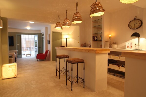 A modern kitchen with a central island, bar stools, pendant lights, and a clock on the wall. - Hostal Juanita (Ibiza Town)