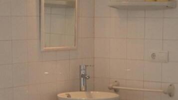 Une salle de bain avec un lavabo blanc, un miroir et un porte-serviettes.