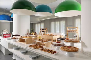 A buffet with various pastries and desserts, including cakes and pastries, arranged on a white table with a modern design. - Love Boat (Riccione)